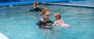 Instructor guiding infant during survival swim lesson at Little Fins Swim School in Colorado Springs