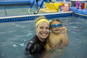 Ms. Kory swimming in Colorado Springs with little boy learning water safety