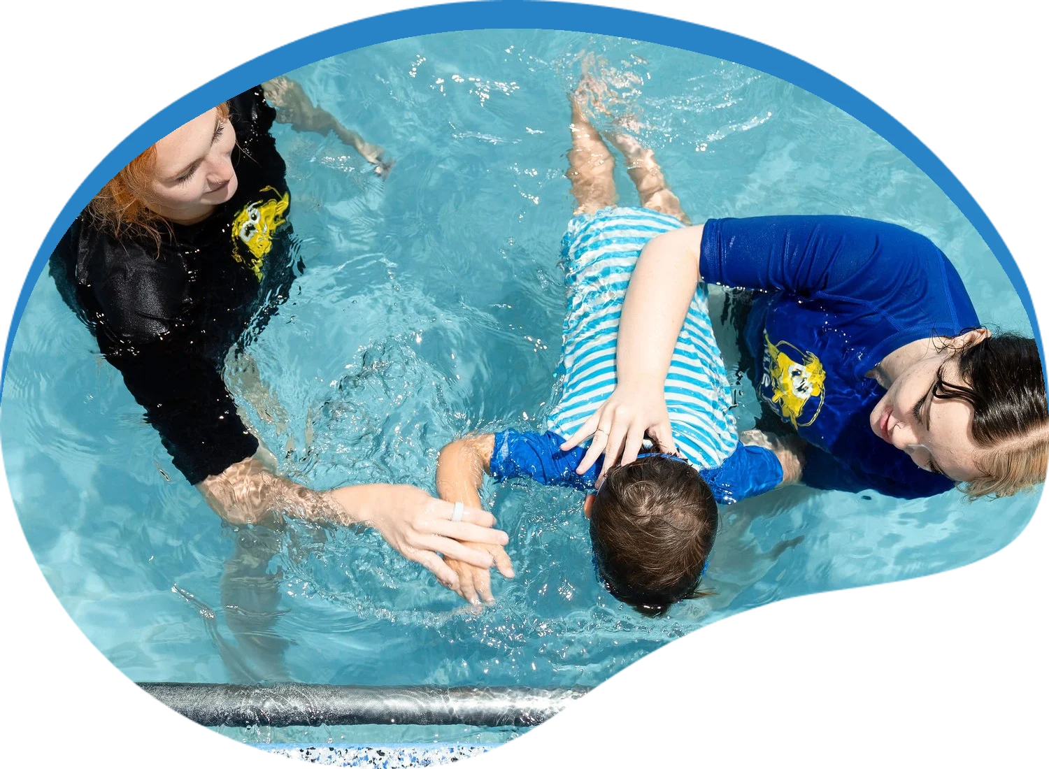 Two Little Fins instructors guiding a young swimmer through a face-down swim during a lesson