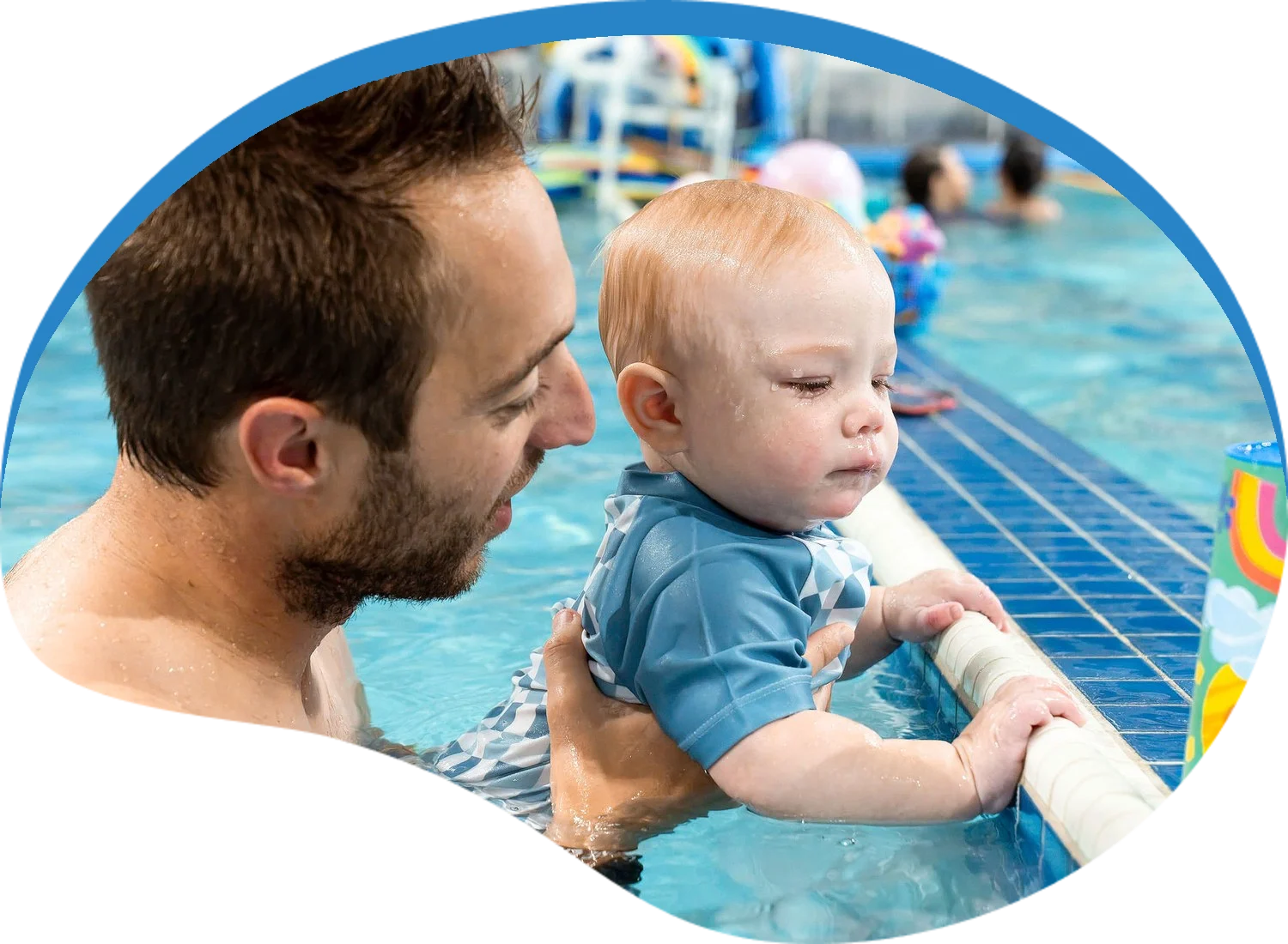 Baby holding onto the pool wall with a parent close by at Little Fins Swim School