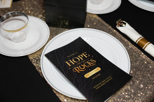 Hope on the Rocks program on a gold and black table setting